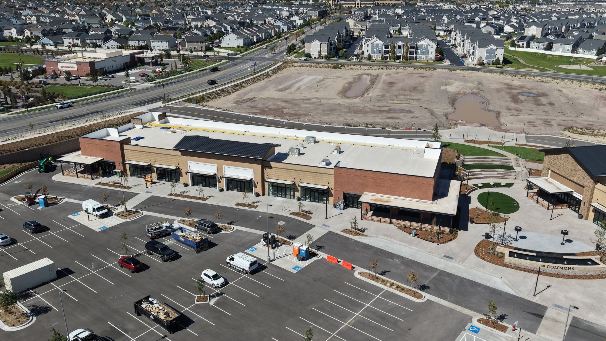 Aerial view of the shops building and plaza at The Commons, with Herriman neighborhoods beyond
